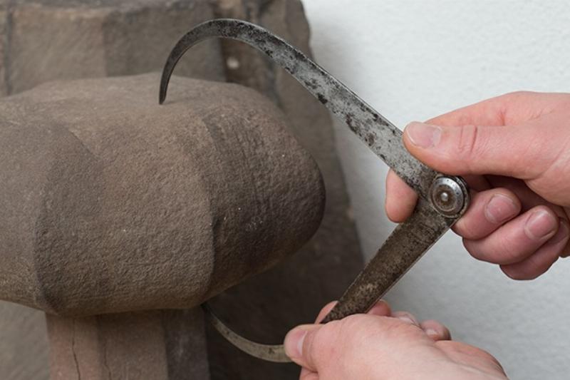 Un artisan tailleur de pierre travaillant sur un bloc de calcaire pour la restauration de la cathédrale Notre-Dame de Paris, avec des outils traditionnels.